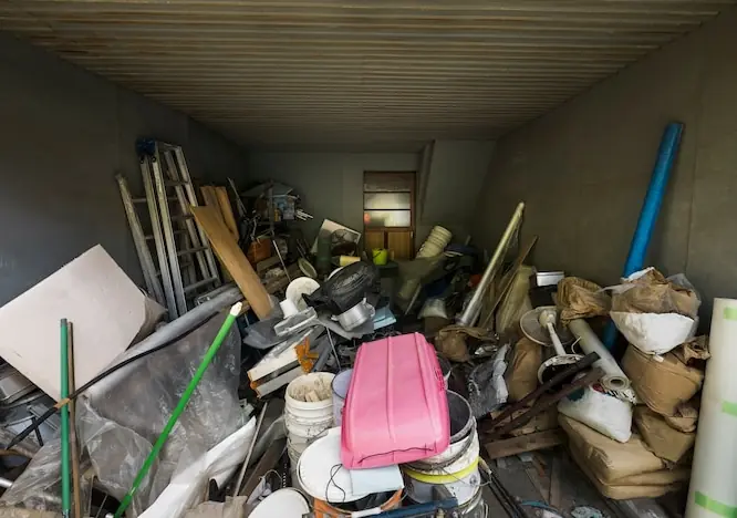 Garaj plin de vechituri, scânduri, țevi și găleți care așteaptă evacuarea gunoiului